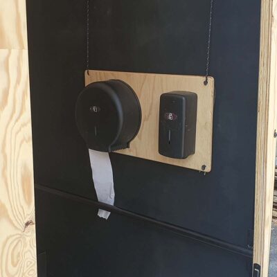 Libre Event 14 Papierhalter und Desinfektionsspender an Holzplatte in der barrierefreien Libre Event Trockentoilette mit schwarzer Innenwand für hygienische Nutzung.