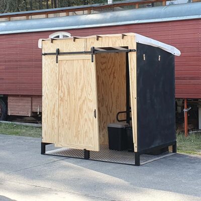 Libre Event 9 Vorderansicht der barrierefreien Libre Event Trockentoilette aus Holz, Schiebetür geöffnet, mit regendichtem weißen Foliendach auf Metallbodenplatte für sicheren und komfortablen Einsatz im Outdoor-Bereich.