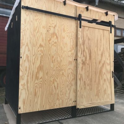 Libre Event 10 Vorderansicht der barrierefreien Libre Event Trockentoilette aus Holz, Fronttür geschlossen, mit regendichtem weißen Foliendach auf Metallbodenplatte für sicheren und komfortablen Einsatz im Outdoor-Bereich.