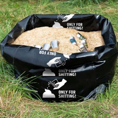 Schwarzer Sack mit Einstreu und mehreren Metallbechern für die Humusspähre Trockentoilette auf Grasfläche.