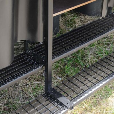 Schwarze Metallgitter-Trittstufen an der Humusspähre Trockentoilette auf grasbewachsenem Untergrund.