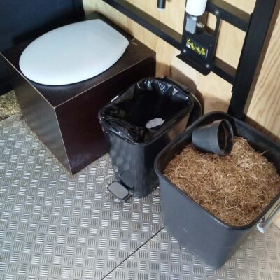 Libre Event 4 Innenansicht der barrierefreien Libre Event Trockentoilette mit Toilettenkasten, Mülleimer für Papier und Einstreu-Eimer mit Stroh und Becher für hygienische Nutzung.