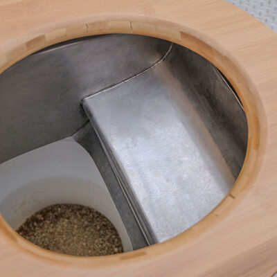 Libre Light 6 Detailansicht des Peepot-Systems in der Libre Trockentoilette mit Edelstahltrennblech und Holzsitz, darunter Auffangbehälter mit Einstreu.