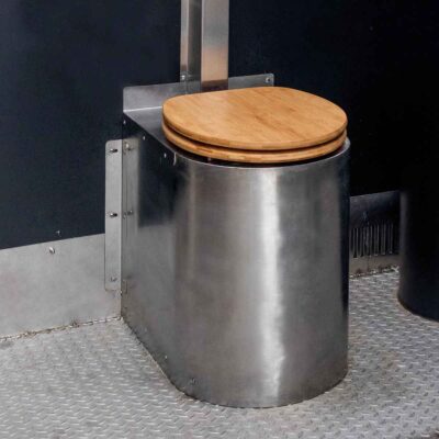 Libre Light 3 Detailansicht Soloo Trockentoilette mit Edelstahltoilette und Holzsitz auf rutschfestem Metallboden vor schwarzer Wand.