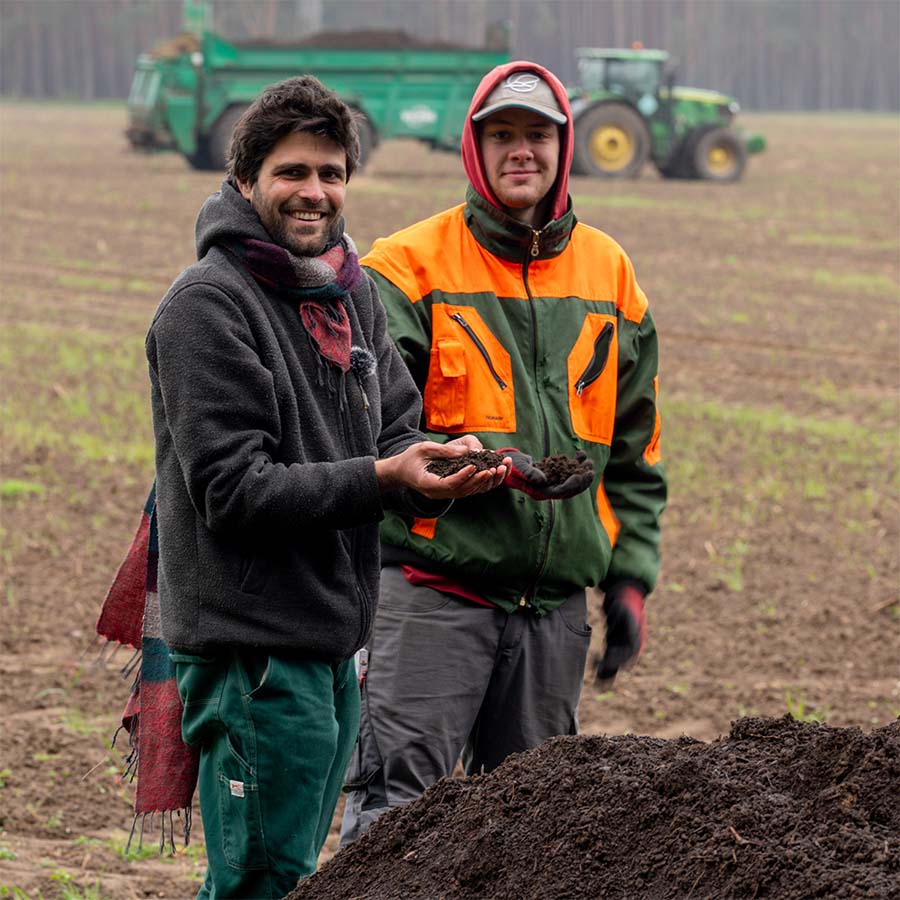 Über uns 2 Florian und unser SuperPraktikant auf dem Versuchsfeld halten HIT in den Händen.