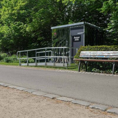 Libre DIN 26 Außenansicht der Libre-DIN Kabine im Ammonpark Eberswalde mit Edelstahlverkleidung und rollstuhlgerechter Zugangsrampe.