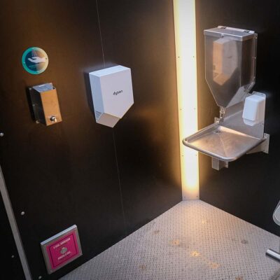 Libre DIN 10 Innenansicht der Libre-DIN Kabine mit Dyson Händetrockner, Edelstahl-Desinfektionsspender und Handwaschstation mit Seifenspender und SOS-Knopf.