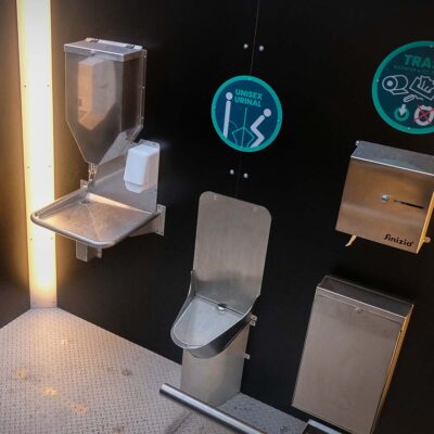 Libre DIN 8 Innenansicht der Libre-DIN Kabine mit Unisexurinal, Papierspender, Handwaschstation und Abfallbehälter.
