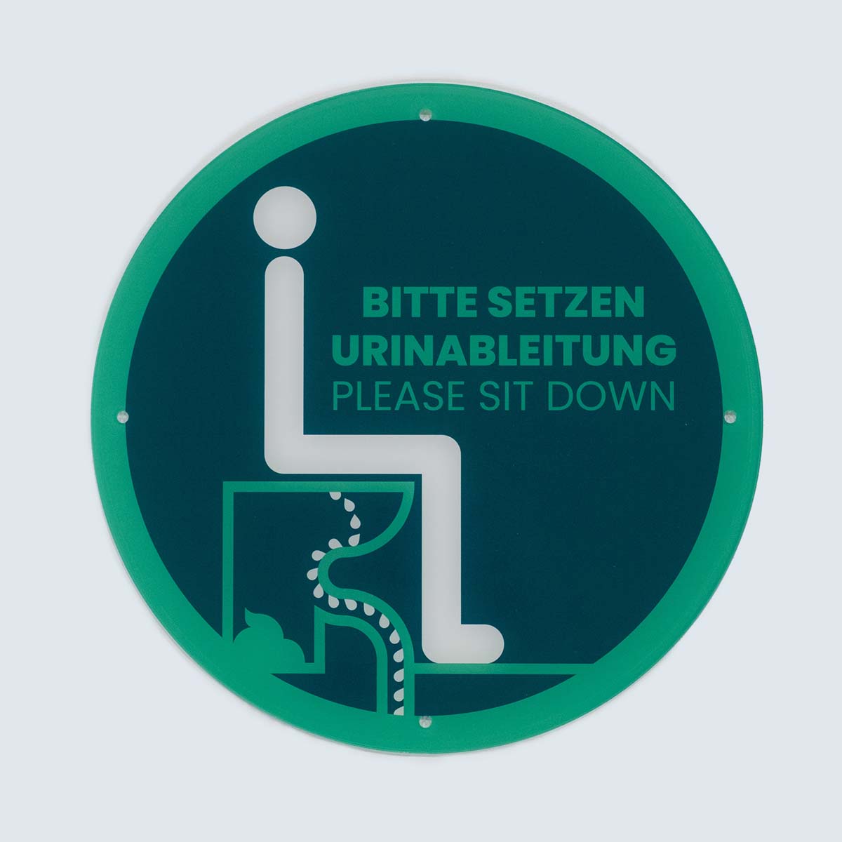 Rundes Hinweisschild aus Acrylglas mit grünem Rand, Piktogramm und Text „Bitte setzen Urinableitung – Please sit down“.