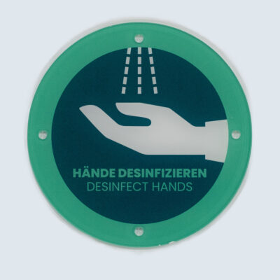 Schilder 6 Rundes Acrylglasschild mit grünem Rand, Text „Hände desinfizieren – Desinfect hands“ und Piktogramm einer Hand unter Desinfektionsspray.