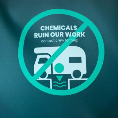 Hinweisschild auf Planeninnenseite der Humussphäre Trockentoilette von Finizio mit Symbol eines durchgestrichenen Wohnmobils und Text „Chemicals ruin our work – contact crew for help“.
