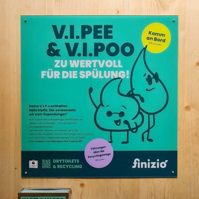 Neues Design: Quadratisches grünes Informationsschild mit Text „V.I.Pee & V.I.Poo zu wertvoll für die Spülung“ und Illustrationen zu Recycling und Nährstoffen an Holzwand.