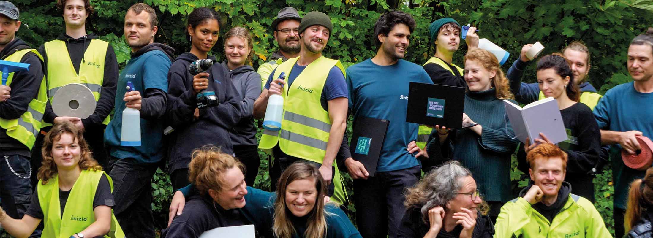 Jobs 1 Mitarbeiter von Finizio in Arbeitskleidung mit Werkzeug, Reinigungsutensilien und Laptop.