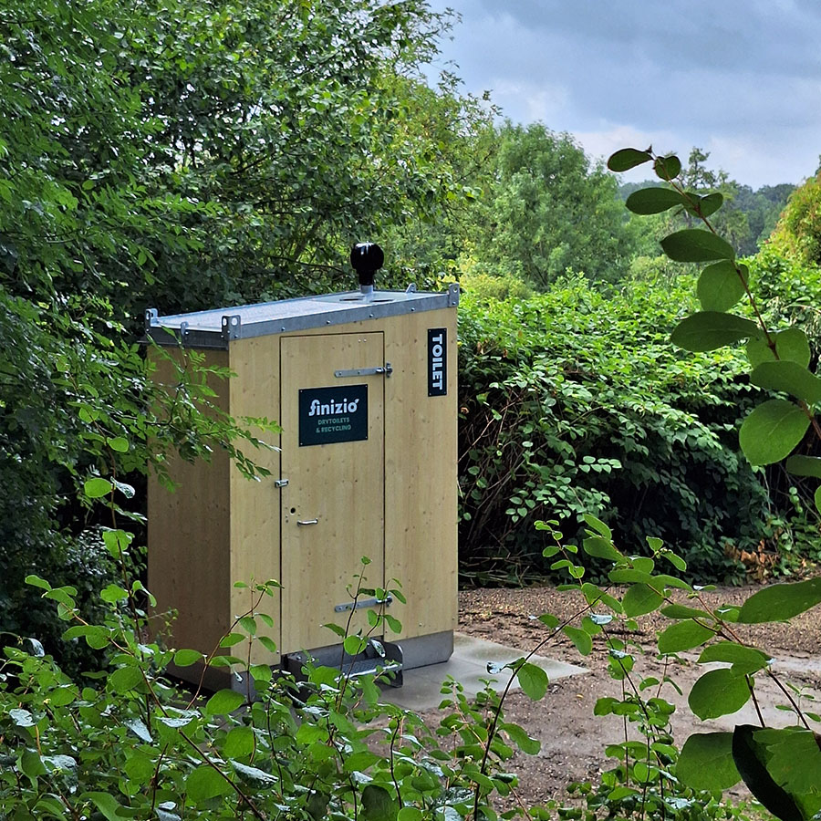 Trockentoiletten und Trenntoiletten 20 Reihen von mobilen Trockentoiletten mit farbigen Bannern und Sammelbehältern auf offenem Gelände bei Sonnenschein