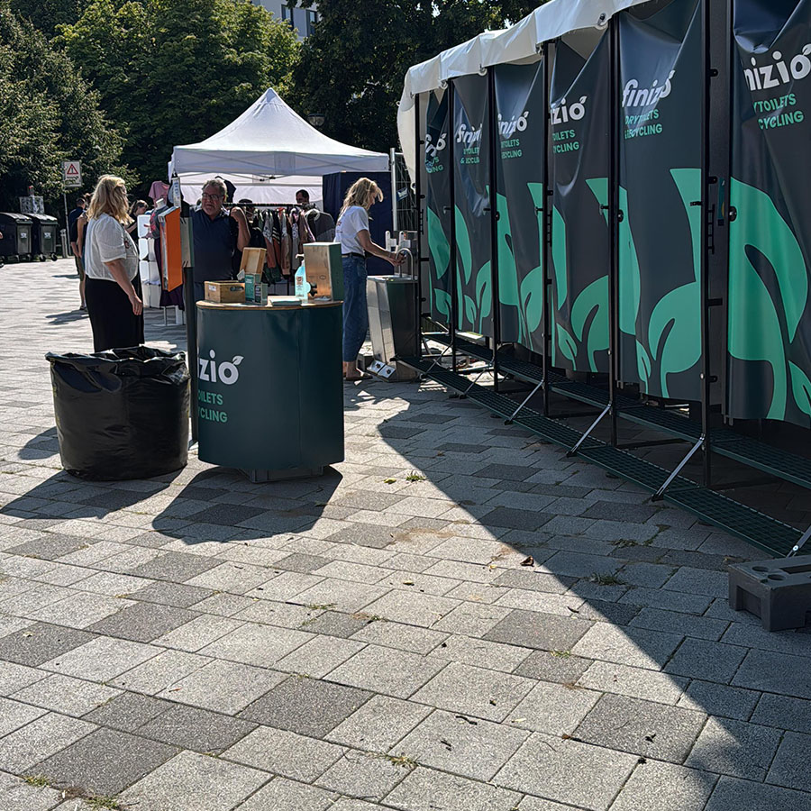 Trockentoiletten und Trenntoiletten 16 Reihen von mobilen Trockentoiletten mit farbigen Bannern und Sammelbehältern auf offenem Gelände bei Sonnenschein